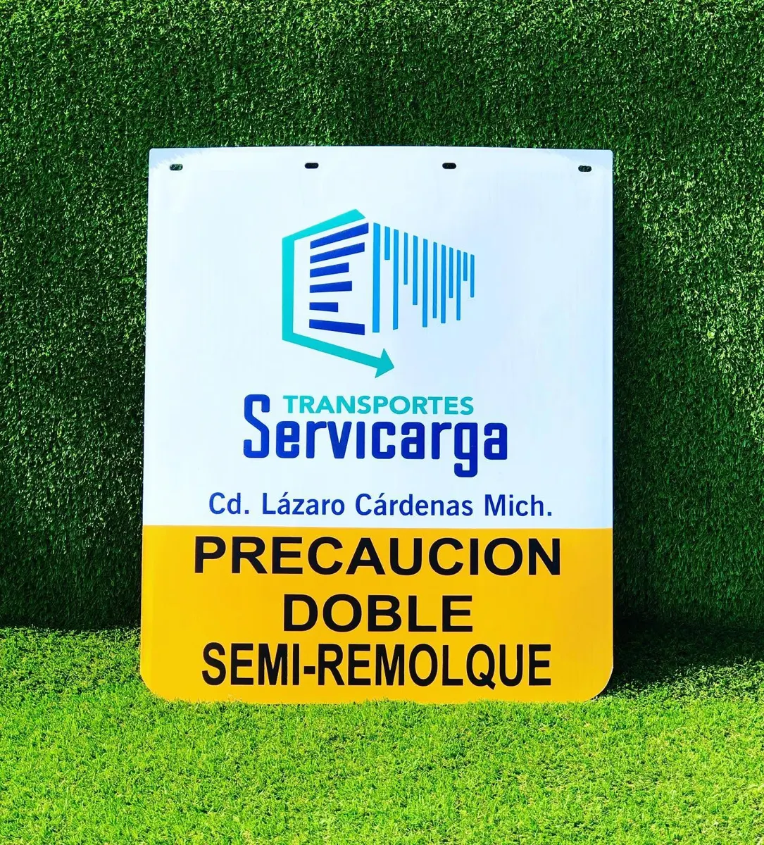 Lodera blanca con logotipo de empresa transportista y franja amarilla con la leyenda Precaución doble semirremolque