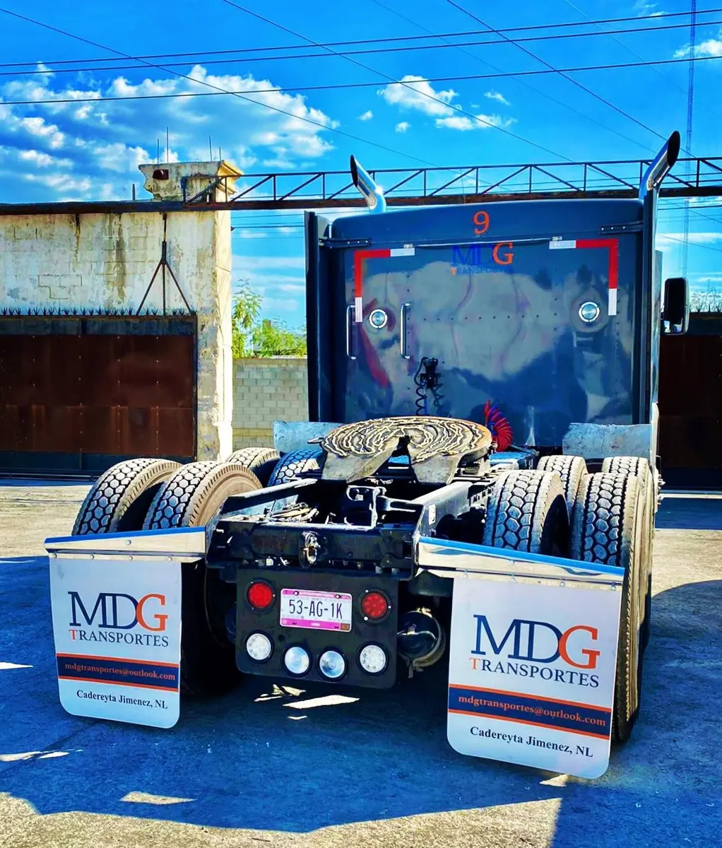Tractocamión visto desde atrás con dos loderas blancas personalizadas con logotipo de empresa de transportes